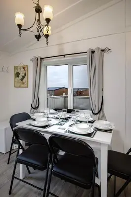 a white table with chairs and wine glasses on it at Tranquil Lodge with river views in Hambleton
