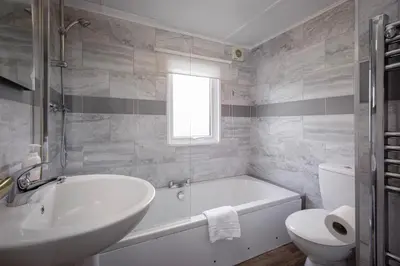 a bathroom with a tub and a sink and a toilet at Tranquil Lodge with river views in Hambleton