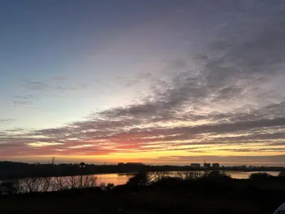 a sunset over a body of water with the sky at Tranquil Lodge with river views in Hambleton
