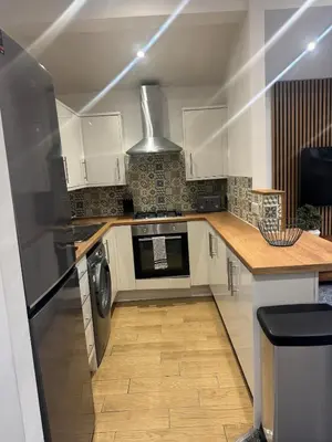 a kitchen with white cabinets and a washer and dryer at Cozy bungalow in Standish