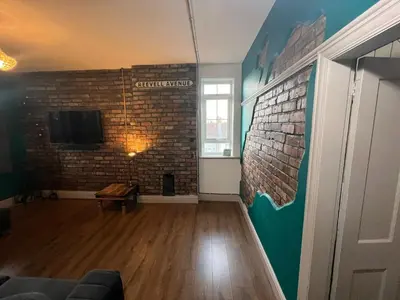a living room with a brick wall and a tv at Reevell Avenue in Liverpool