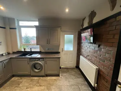 a kitchen with a washing machine and a brick wall at Reevell Avenue in Liverpool
