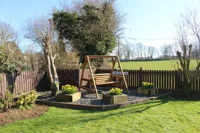 a swing in a garden with flowers in a yard at Hornby Cottage in Saint Michaels on Wyre