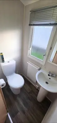 a bathroom with a toilet and a sink and a window at Vanhalla in Heysham