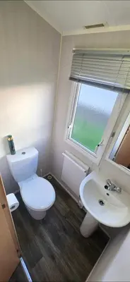 a bathroom with a toilet and a sink and a window at Vanhalla in Heysham
