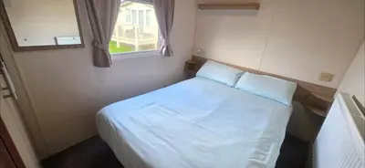 a small bedroom with a white bed with a window at Vanhalla in Heysham