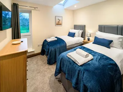 a hotel room with two beds and a desk at Bay Bungalow in Bolton le Sands