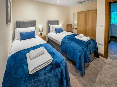 two beds in a room with blue and white sheets at Bay Bungalow in Bolton le Sands