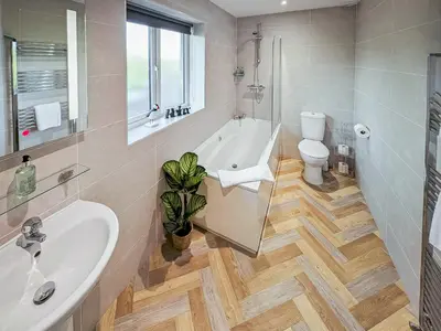 a bathroom with a tub and a toilet and a sink at Bay Bungalow in Bolton le Sands