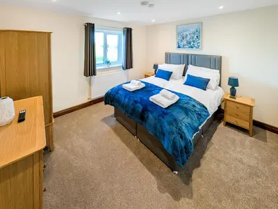 a bedroom with a bed with a blue blanket at Bay Bungalow in Bolton le Sands