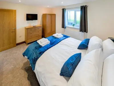 a bedroom with a large white bed with blue pillows at Bay Bungalow in Bolton le Sands