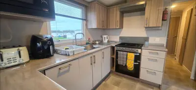 a kitchen with white cabinets and a stove top oven at S & S Retreat in Heysham