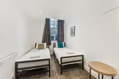 a room with two beds and a table and a window at The Slater Pad - Party Apartment in Liverpool City Centre in Liverpool