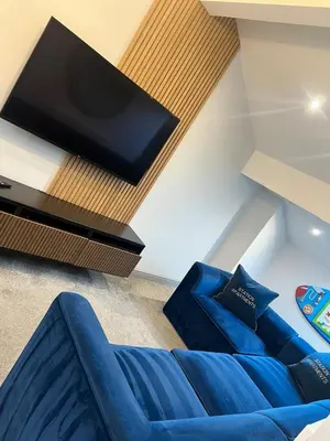 a living room with a blue couch and a flat screen tv at Station View Apartments in Blackpool