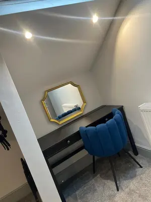 a blue chair in a room with a mirror at Station View Apartments in Blackpool