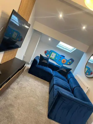 a living room with a blue couch and a flat screen tv at Station View Apartments in Blackpool