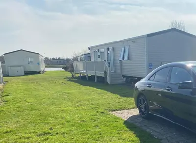 a car parked next to a trailer and a house at Haven Lakeside View Caravan in Flookburgh