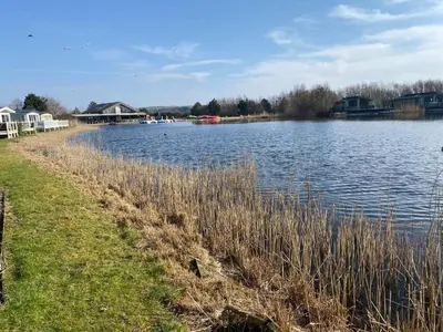 a body of water with houses in the background at Haven Lakeside View Caravan in Flookburgh