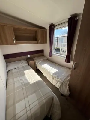 two beds in a small room with a window at Lakeland Holiday Home in Flookburgh