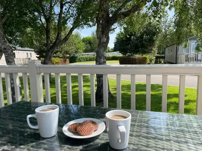 two cups of coffee and croissants on a table on a porch at Lakeland Holiday Home in Flookburgh