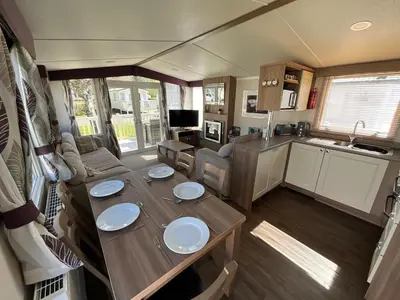 a kitchen and a dining table in a caravan at Lakeland Holiday Home in Flookburgh