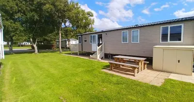 a house with a picnic table in a yard at Lakeland Holiday Home in Flookburgh