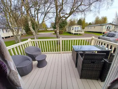 a porch with a table and stools on a deck at Lakeland Holiday Home in Flookburgh