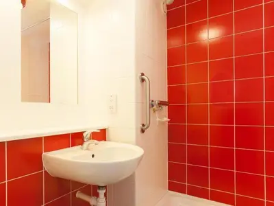 a bathroom with a sink and red tiles at Travelodge Liverpool Stonedale Park in Liverpool