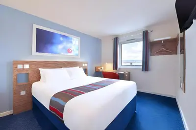 a hotel room with a large white bed and a window at Travelodge Liverpool Stonedale Park in Liverpool