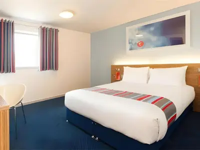 a hotel room with a large bed and a table at Travelodge Morecambe in Morecambe