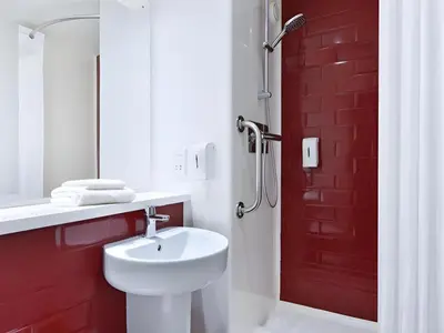 a bathroom with a white sink and a red brick wall at Travelodge Morecambe in Morecambe