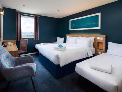 a hotel room with two beds and a chair at Travelodge Blackpool South Shore in Blackpool