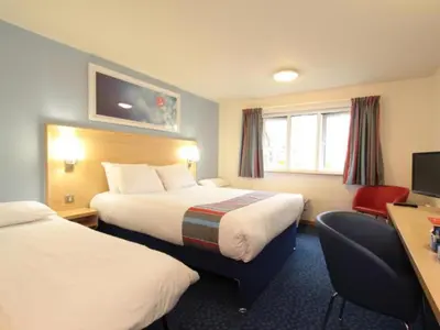 a hotel room with two beds and a desk at Travelodge Preston Central in Preston