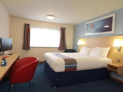 a hotel room with a bed and a desk with a computer at Travelodge Preston Central in Preston