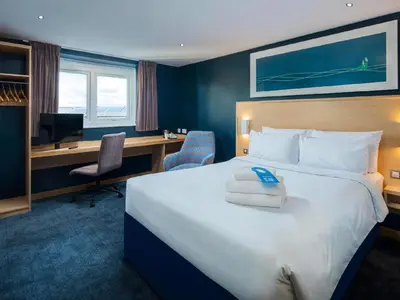 a hotel room with a large bed and a desk at Travelodge Preston Central in Preston