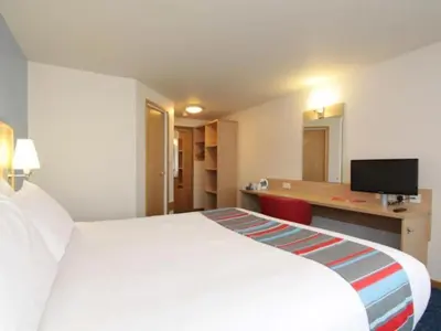 a hotel room with a large white bed and a desk at Travelodge Preston Central in Preston