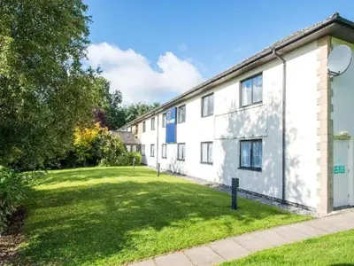 a large white building with a grass yard at Travelodge Burton M6 Northbound in Holme
