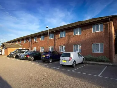 a group of cars parked in front of a brick building at Travelodge Barrow In Furness in Barrow in Furness