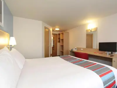 a hotel room with a large white bed and a desk at Travelodge Barrow In Furness in Barrow in Furness
