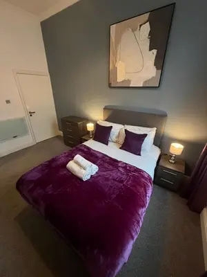 a bedroom with a large bed with purple sheets and pillows at City Centre 4 Bedroom Apartment with Terrace Sleeps 10 by StaySavvy Accommodation in Liverpool