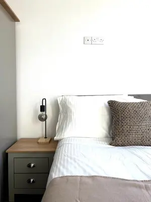 a bedroom with a bed with white sheets and a night stand at Contractors House - 10 Seperate Beds - FREE Parking in Liverpool