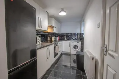 a kitchen with white cabinets and a washer and dryer at Charming & Relaxing Getaway near Liverpool City in Liverpool