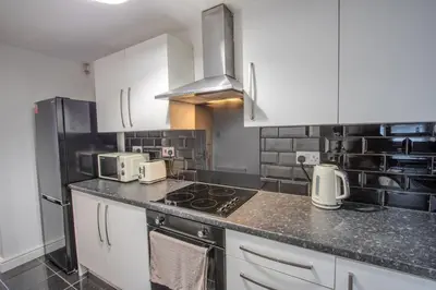 a kitchen with white cabinets and a stove top oven at Charming & Relaxing Getaway near Liverpool City in Liverpool