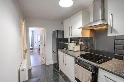 a kitchen with white cabinets and a stove top oven at Charming & Relaxing Getaway near Liverpool City in Liverpool