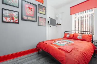 a bedroom with a bed with a red blanket at The Red One-Sleeps 16, near Anfield & City Centre in Liverpool