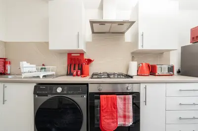 a kitchen with a dishwasher and a stove with red towels at The Red One-Sleeps 16, near Anfield & City Centre in Liverpool