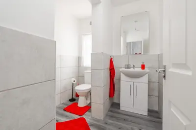 a white bathroom with a toilet and a sink at The Red One-Sleeps 16, near Anfield & City Centre in Liverpool