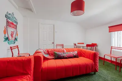 a red couch in a room with red chairs at The Red One-Sleeps 16, near Anfield & City Centre in Liverpool