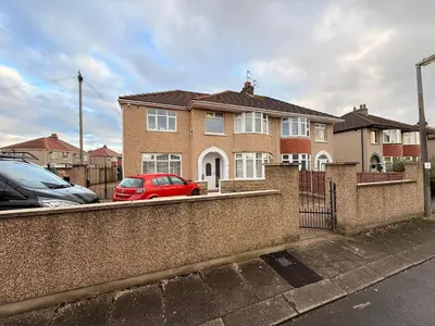 a red car parked in front of a brick house at Sanders Grove in Morecambe
