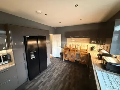 a kitchen with black cabinets and a wooden floor at Sanders Grove in Morecambe